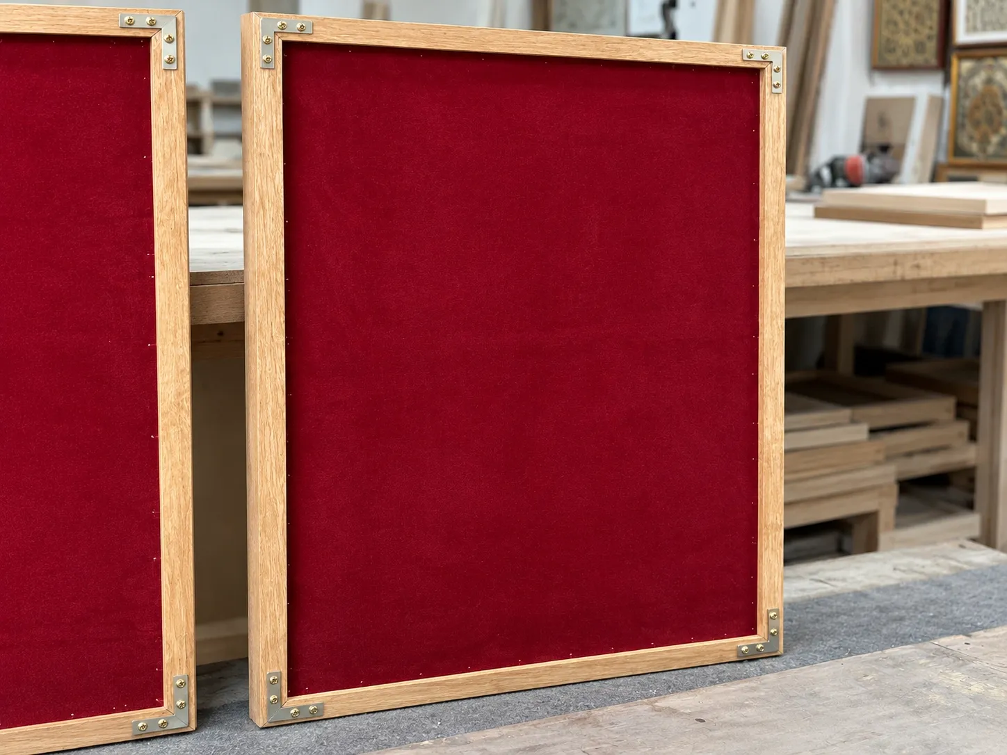 The backs of two light wood frames covered in red fabric, with metal brackets at the corners.