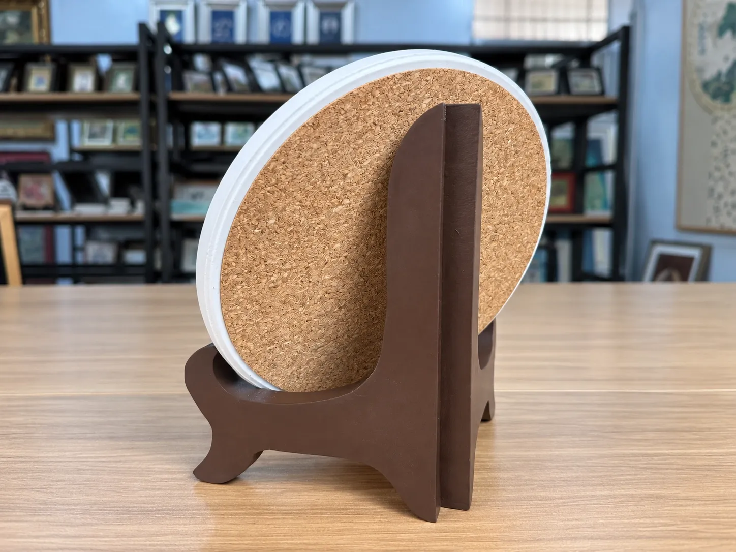 The back of a round disc with a cork backing, resting in a dark wooden stand.