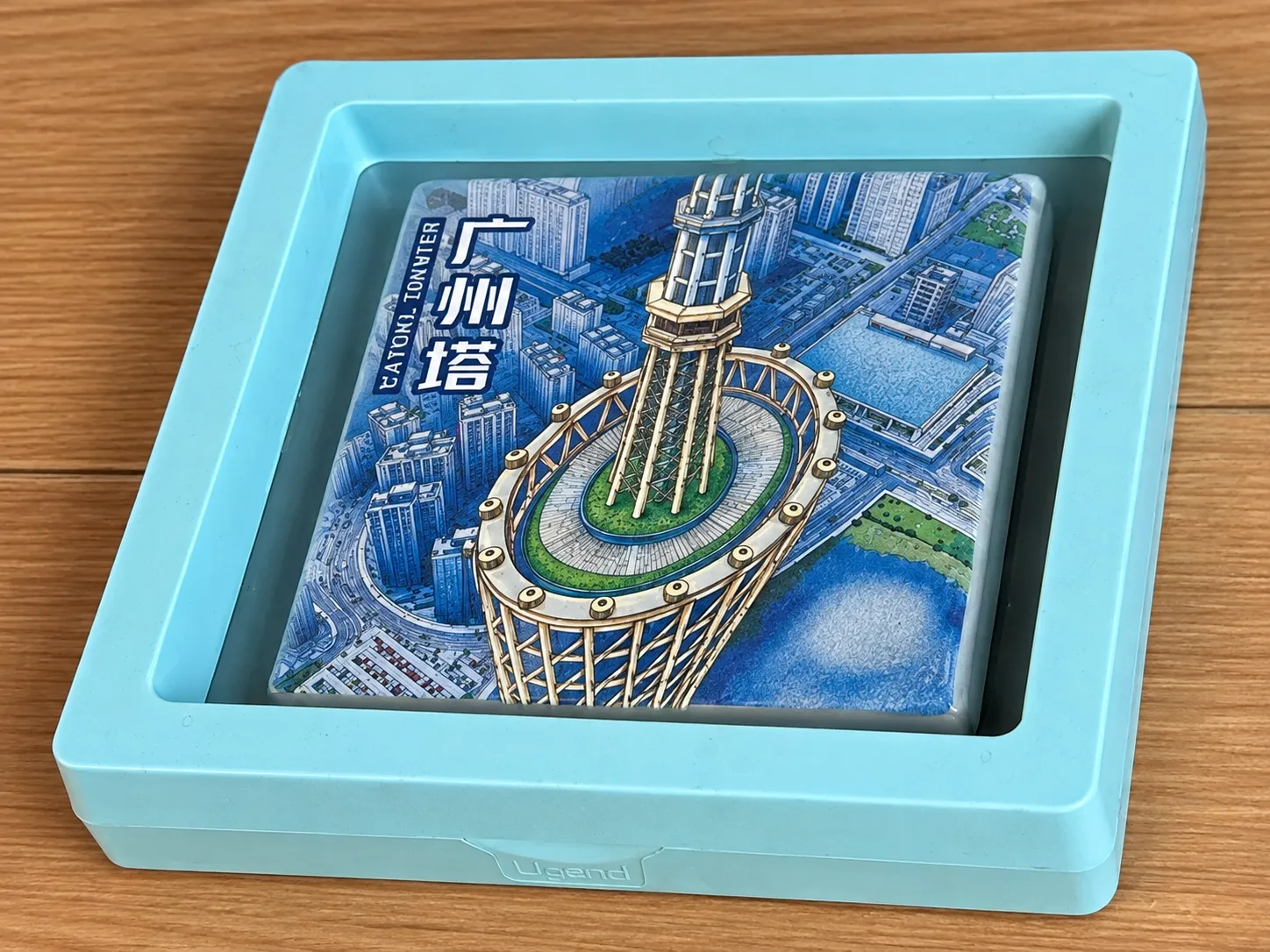A square ceramic fridge magnet of Canton Tower sitting in a light-blue floating display box.