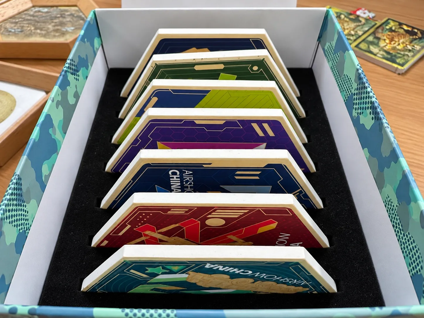 A printed gift box holding a series of shaped Airshow China pieces, each standing upright in a fitted black foam insert.