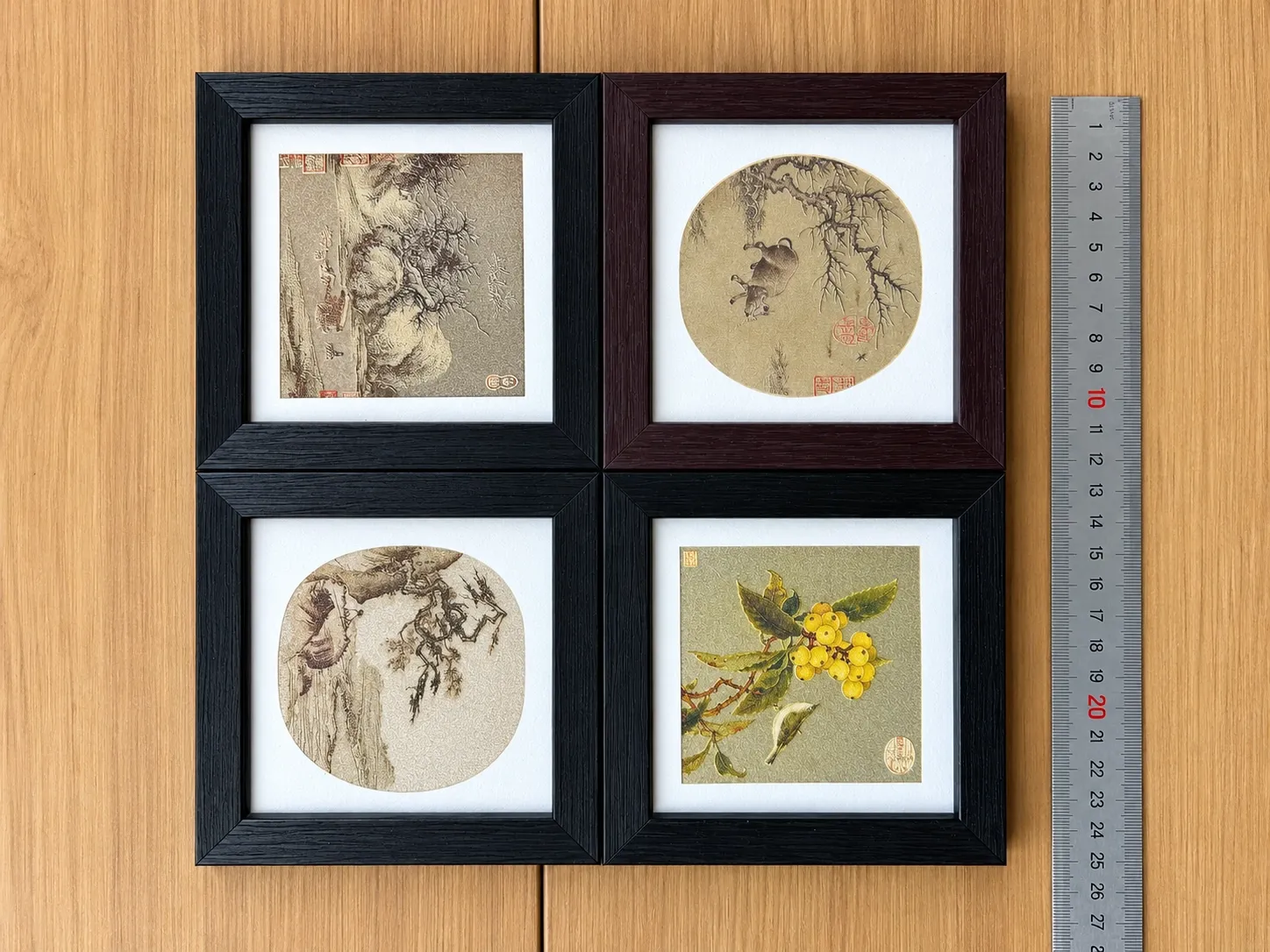 Four framed fridge magnets with classical paintings, a steel ruler alongside for scale.