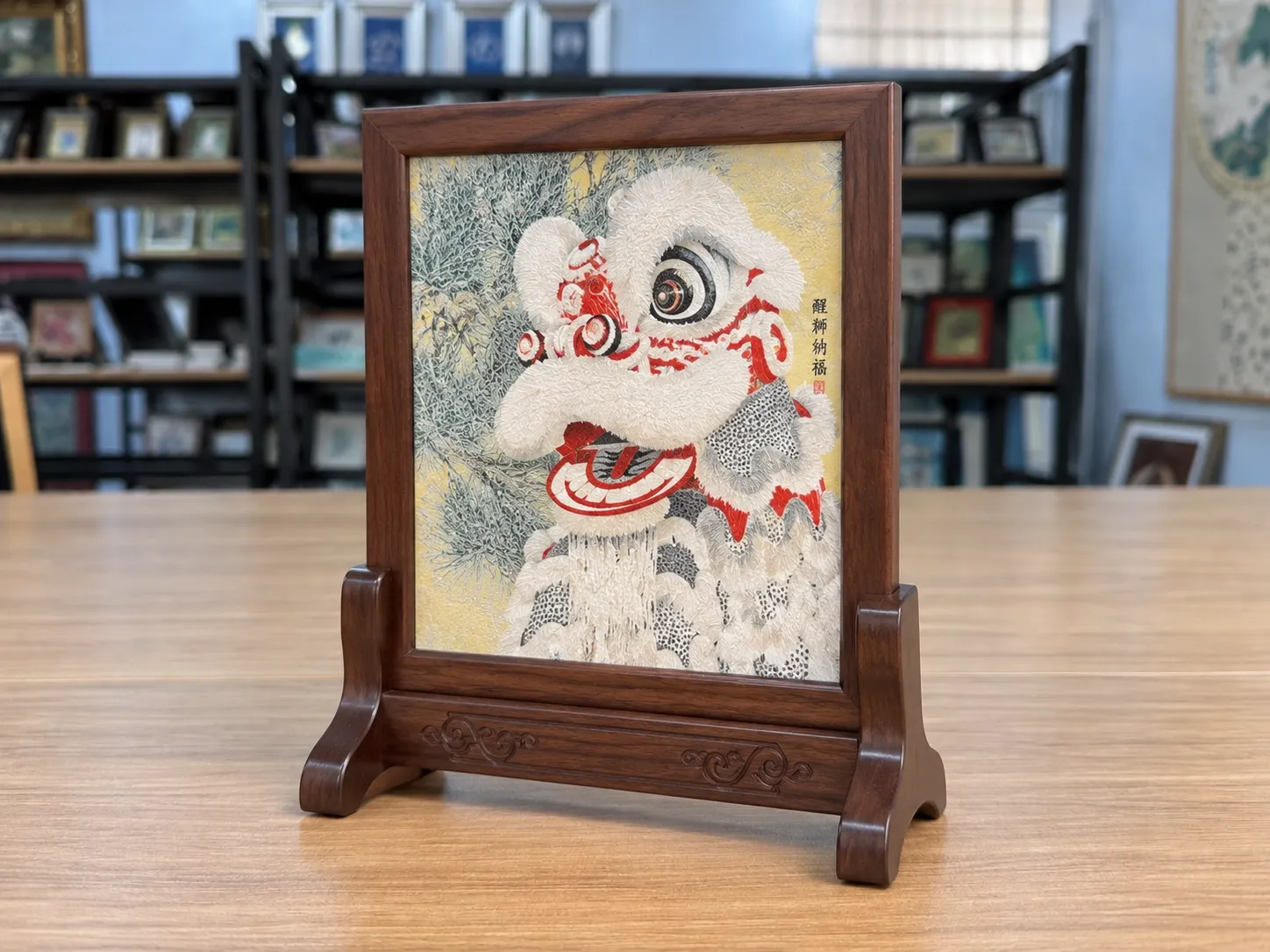 A white lion-dance piece held upright in a dark wood table-screen stand on a desk.