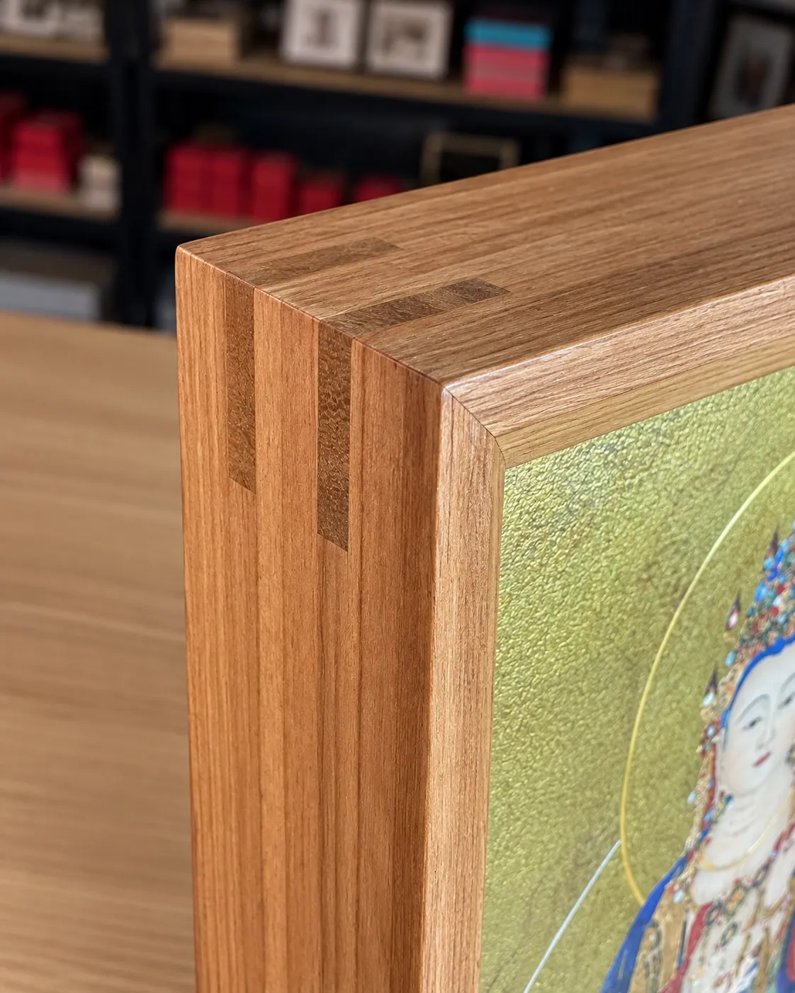 Close view of a solid wood frame corner with two dark wood keys across the mitre, showing the depth of the side return.