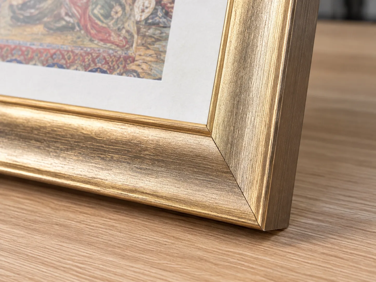 Close view of a gold-tone PS frame corner with a closed mitre, artwork and a white border inside.