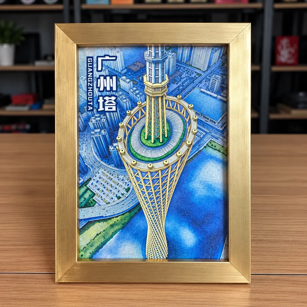 A framed piece showing Canton Tower in Guangzhou, in a brushed gold-tone frame.