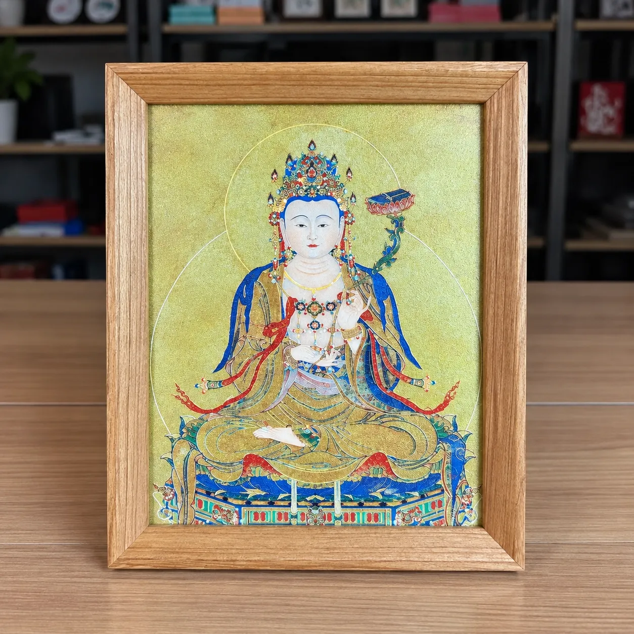 A framed figure piece in a light wood frame, standing on a desk.