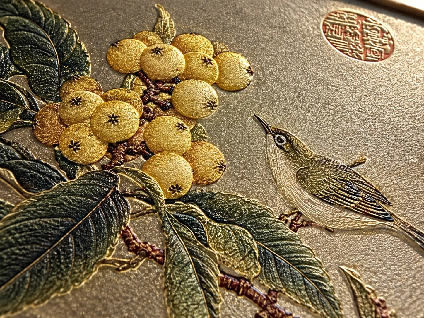 Relief of loquat fruit, leaves and a small bird on a gold-tone ground, seen at an angle.