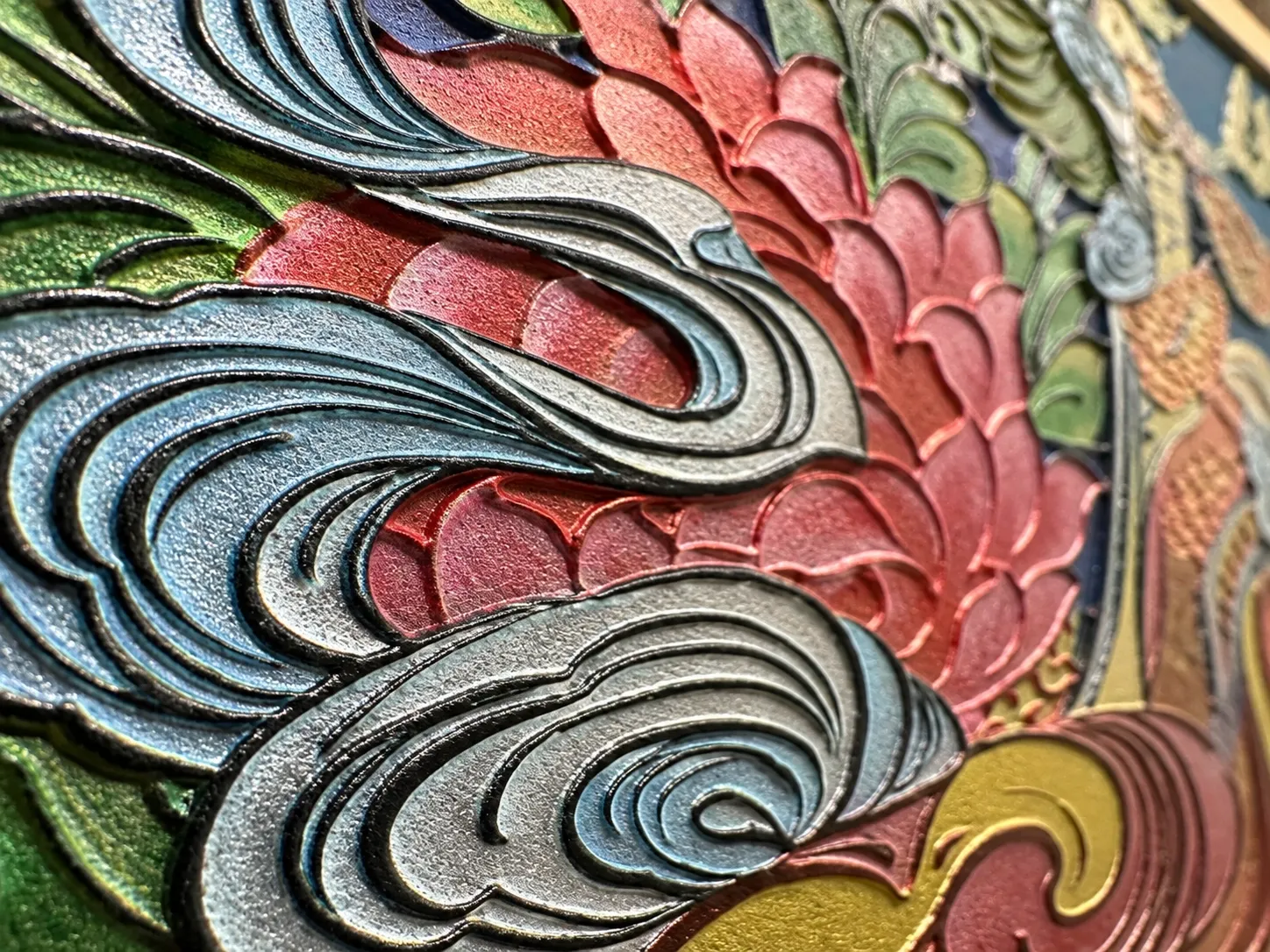 Close view of a Thangka relief: cloud and lotus forms whose dark outlines follow each raised edge.