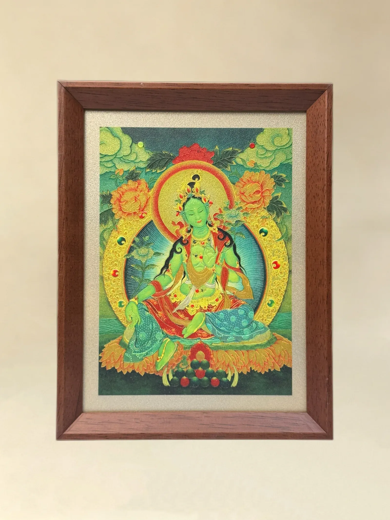 A relief artwork of Green Tara, golden halo, as a desktop frame, photographed front on.