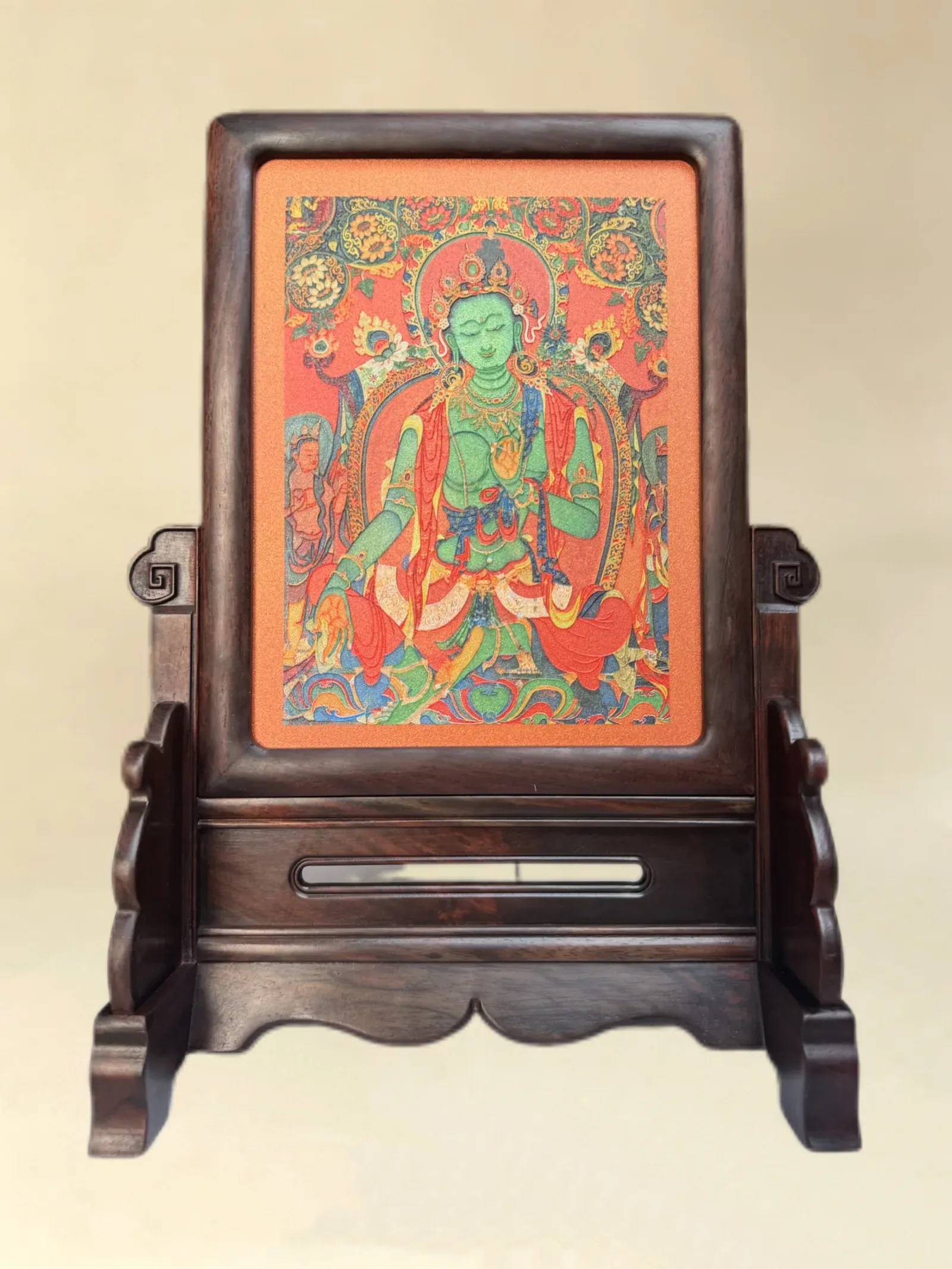 A relief artwork of Green Tara, red ground, as a table screen, photographed front on.